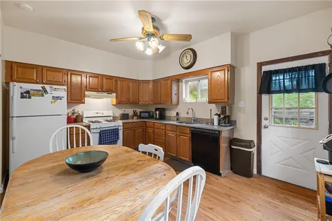 a kitchen with stainless steel appliances granite countertop a refrigerator a stove a sink dishwasher and a dining table with wooden floor