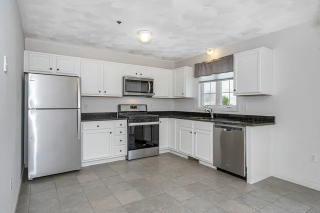 a kitchen with stainless steel appliances granite countertop a refrigerator sink stove microwave and cabinets
