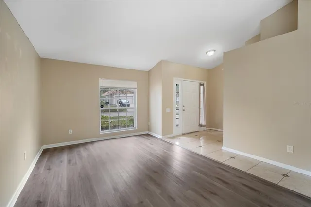 a view of an empty room with wooden floor and a window