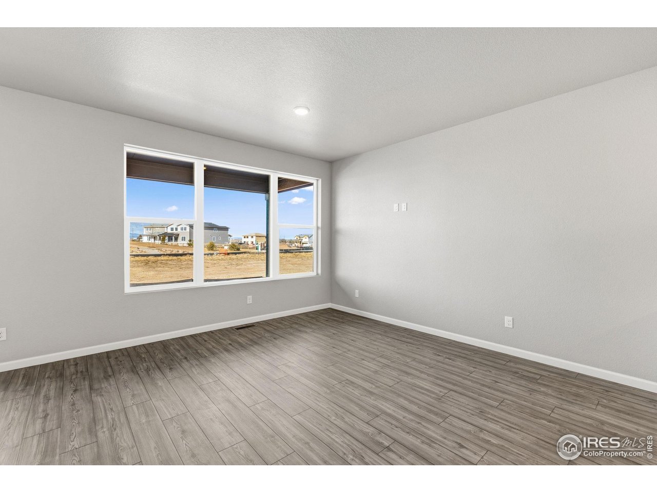 6793 Utica Court Firestone, CO 80504 - Photo 11 of 26 a view of an empty room with wooden floor and a window