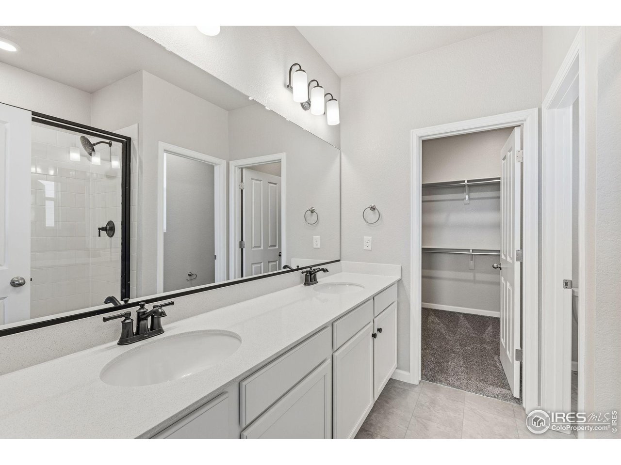 6793 Utica Court Firestone, CO 80504 - Photo 16 of 26 a bathroom with a double vanity sink a mirror and a shower