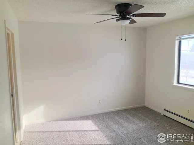 an empty room with a window and a fan