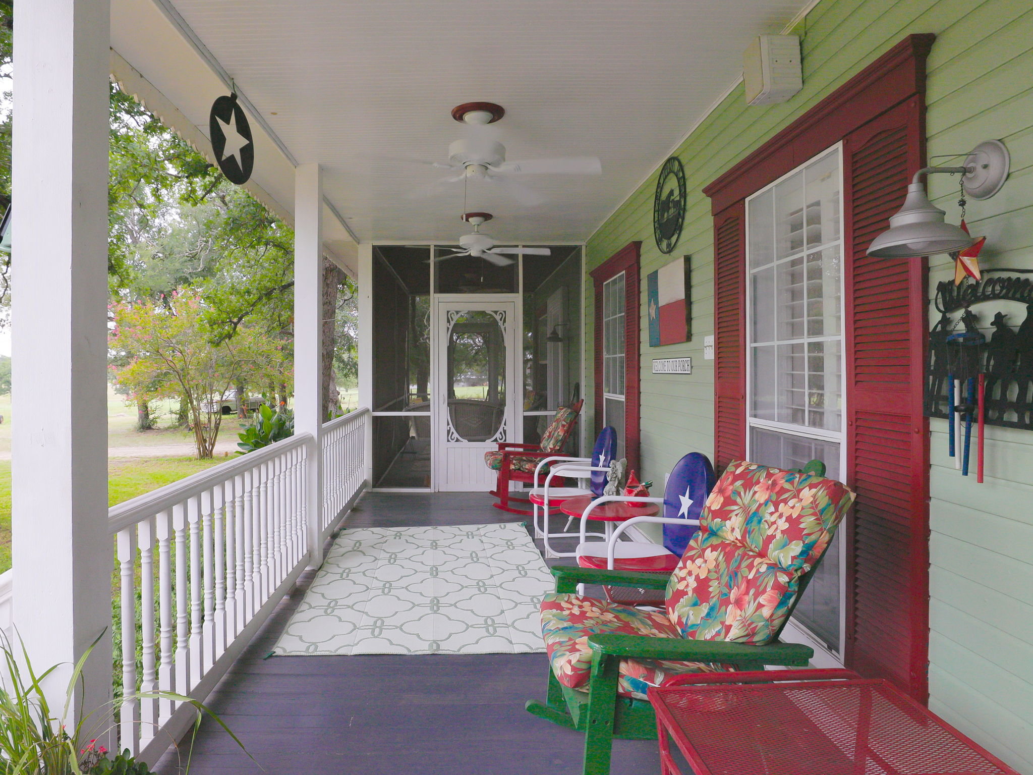 1065 Private Road 7041 Elgin, TX 78621 - Photo 2 of 38 Front covered patio featuring two ceiling fans to keep you cool while you relax and enjoy breathtaking sunsets. Overlooking a large open yard dotted with plenty of mature trees, this welcoming outdoor space is perfect for entertaining or quiet evenings