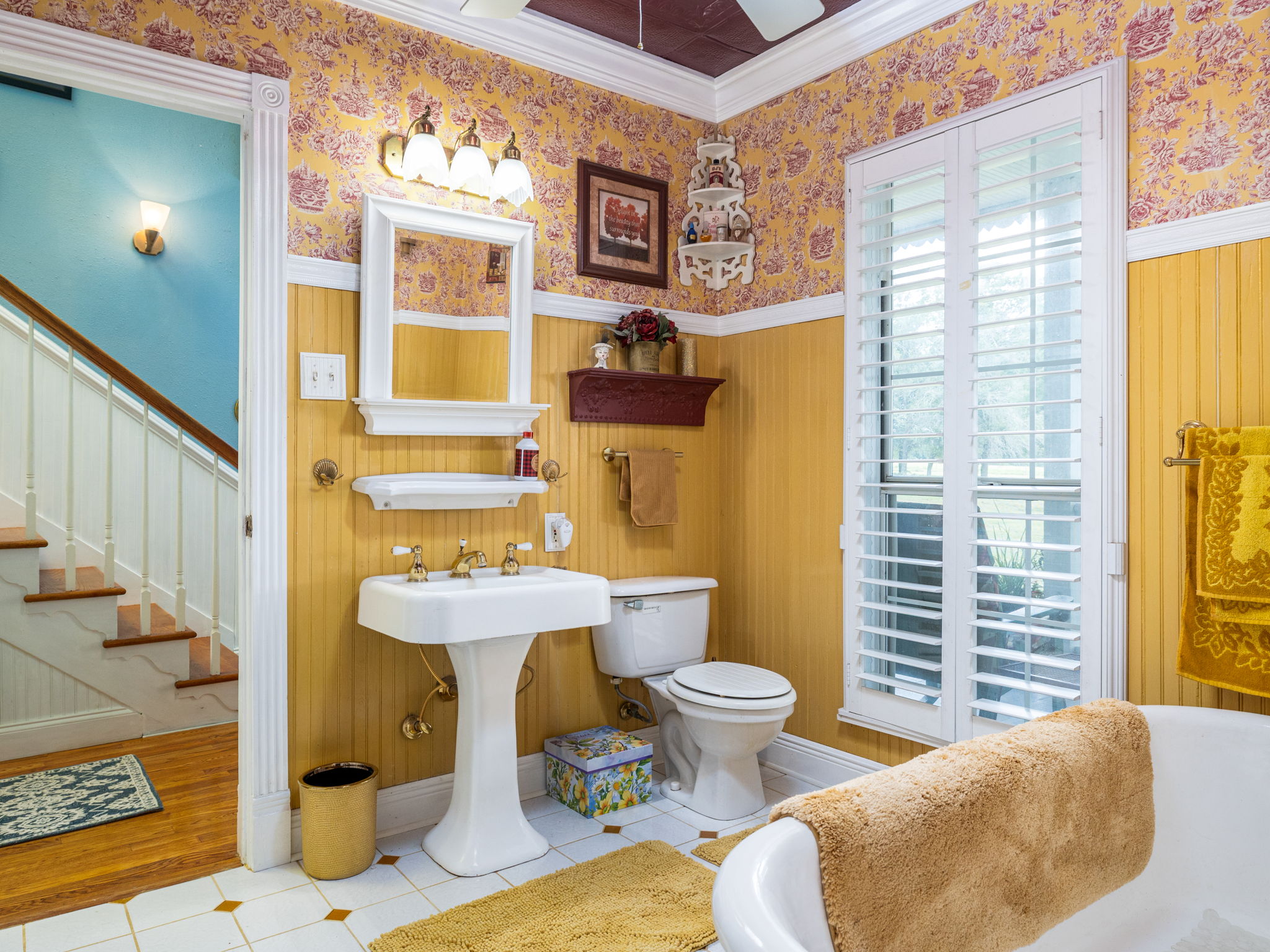 1065 Private Road 7041 Elgin, TX 78621 - Photo 4 of 38 Full bathroom showcases exquisite crown molding and plantation shutters that provide both privacy and style. The walls and trim feature intricate detailing, enhancing the room’s classic charm. A ceiling fan ensures comfort and airflow, making this space both elegant and functional