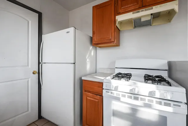 a white refrigerator freezer and a stove sitting inside of a kitchen
