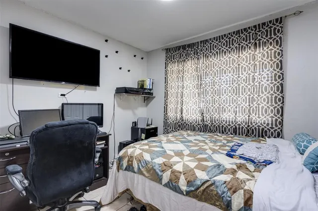 a bedroom with a bed tv and a window