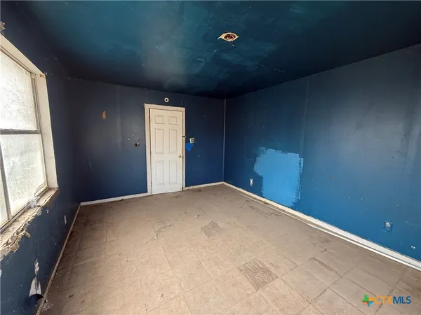 a white house that has a small yard and a large trees with wooden fence