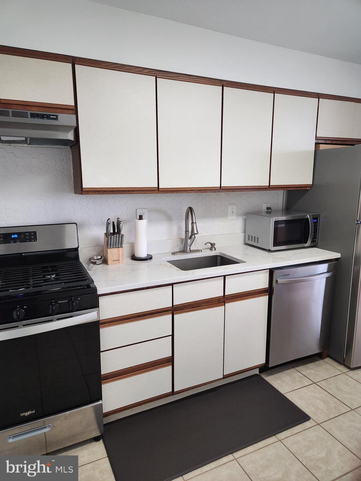 3900 West Ford Road, Unit 12A Philadelphia, PA 19131 - Photo 17 of 46 a kitchen with white cabinets a sink and a stove