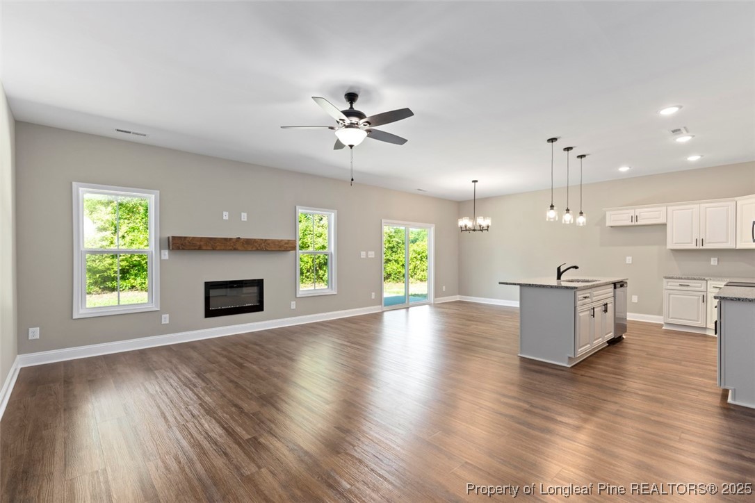 5578 Philippi Church Road Raeford, NC 28376 - Photo 19 of 33 a view of a kitchen with a fireplace a ceiling fan and wooden floor