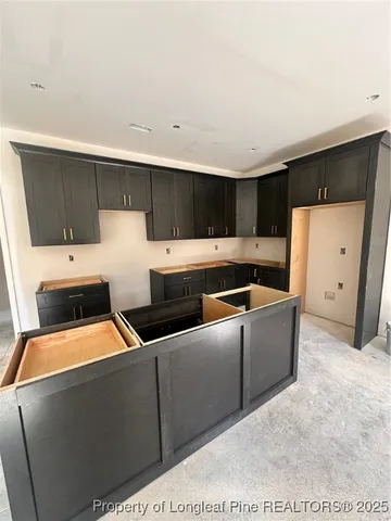 a kitchen with a stove a sink a refrigerator and white cabinets with wooden floor