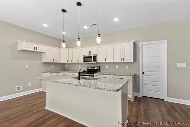 a kitchen with granite countertop kitchen island white cabinets and a chandelier