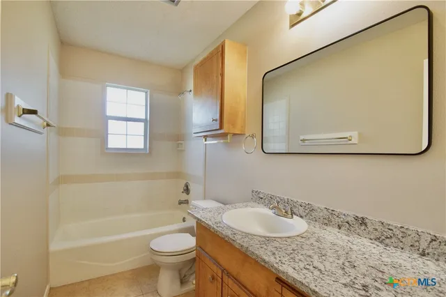 a bathroom with a granite countertop sink toilet and a mirror