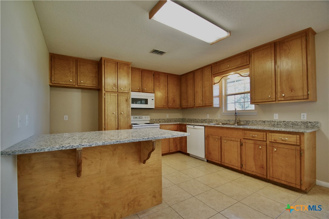 102 Owl Road Victoria, TX 77905 - Photo 3 of 19 a large kitchen with granite countertop a sink stainless steel appliances and cabinets