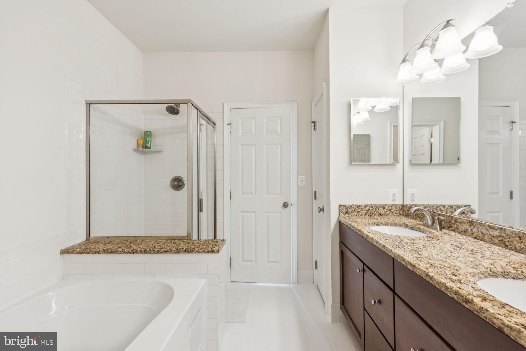 105 Commodore Court Philadelphia, PA 19146 - Photo 15 of 26 a bathroom with a granite countertop sink a mirror a shower and a bathtub