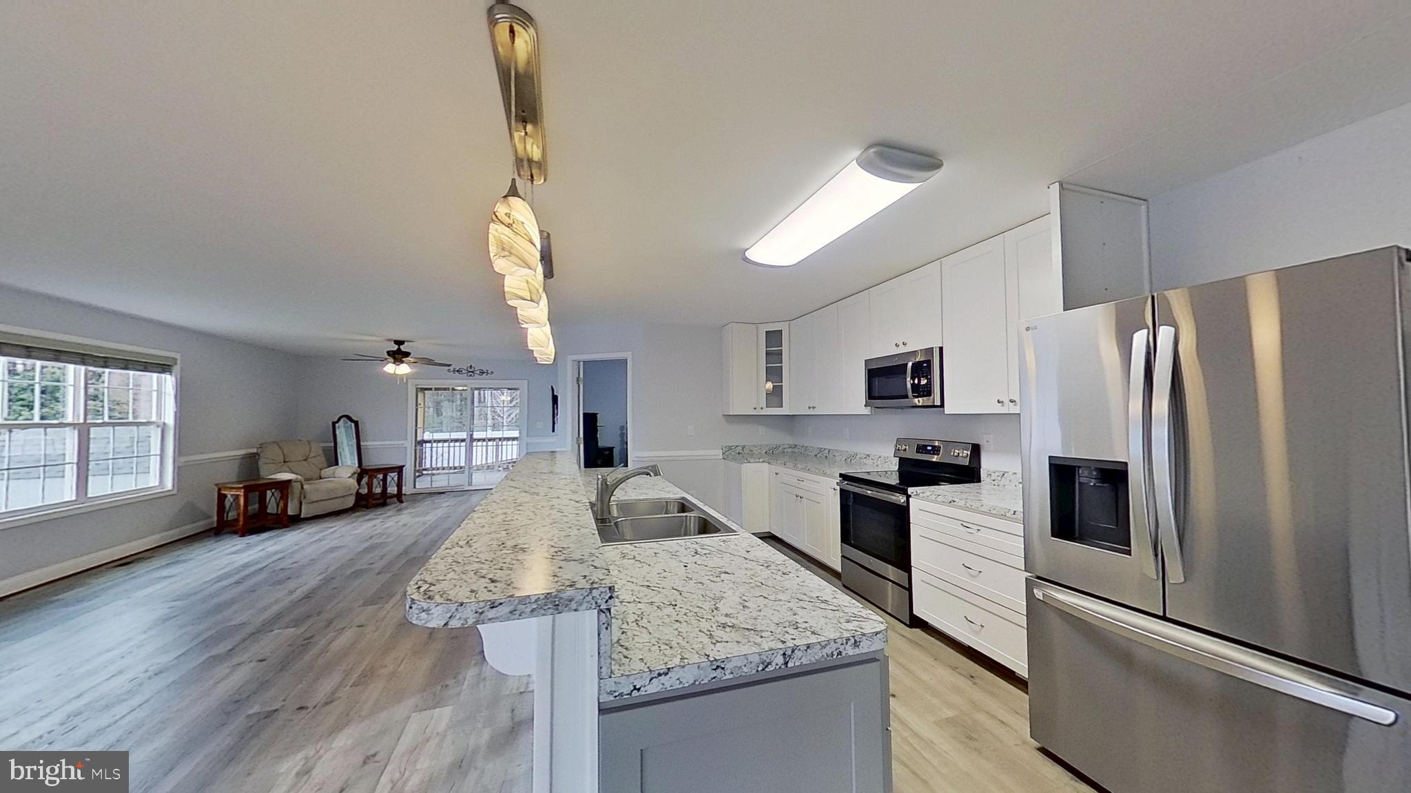 95 Rolando Drive Colonial Beach, VA 22443 - Photo 13 of 39 a kitchen with stainless steel appliances granite countertop a refrigerator a stove a sink dishwasher a oven with white cabinets and wooden floor