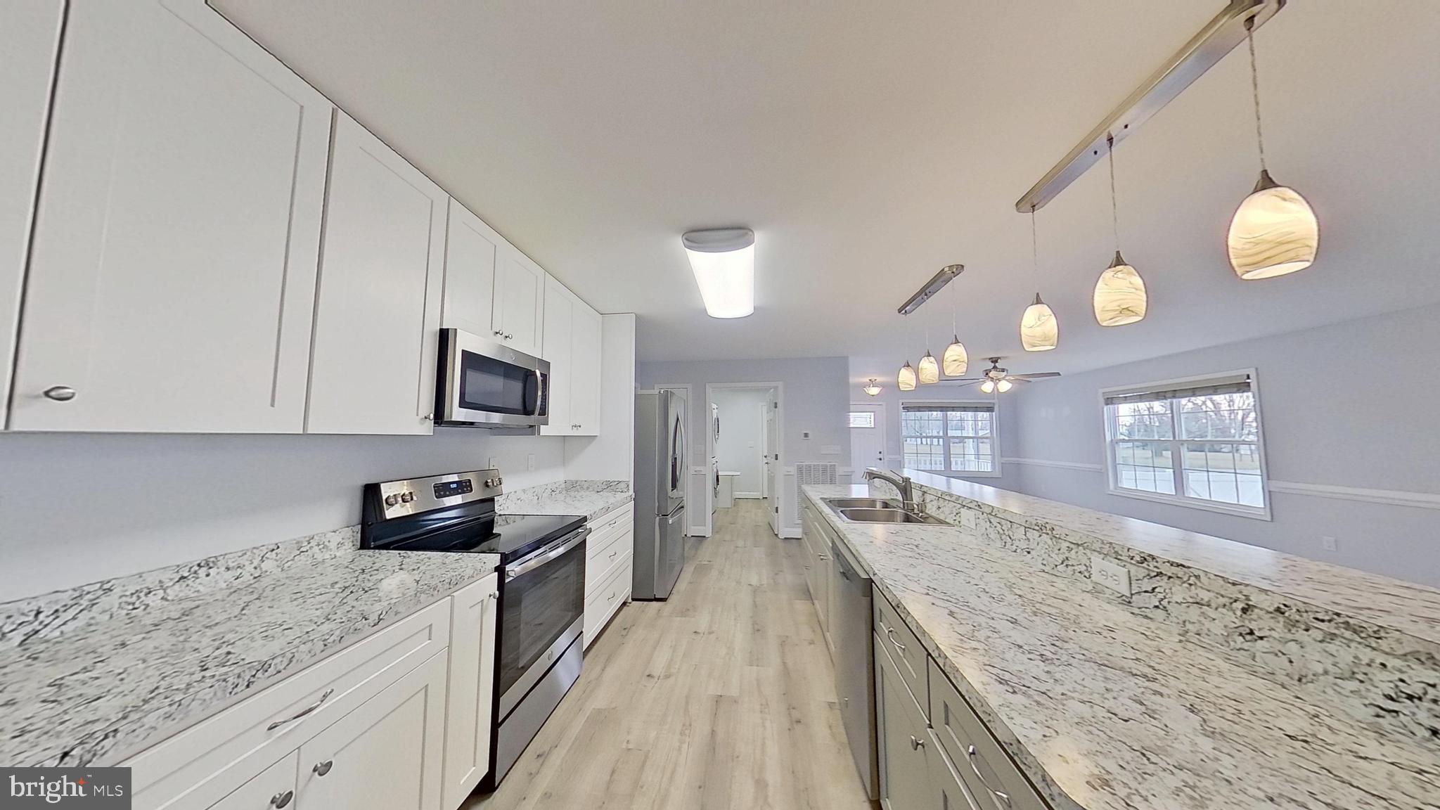 95 Rolando Drive Colonial Beach, VA 22443 - Photo 14 of 39 a kitchen with granite countertop a sink dishwasher stove and cabinets with wooden floor