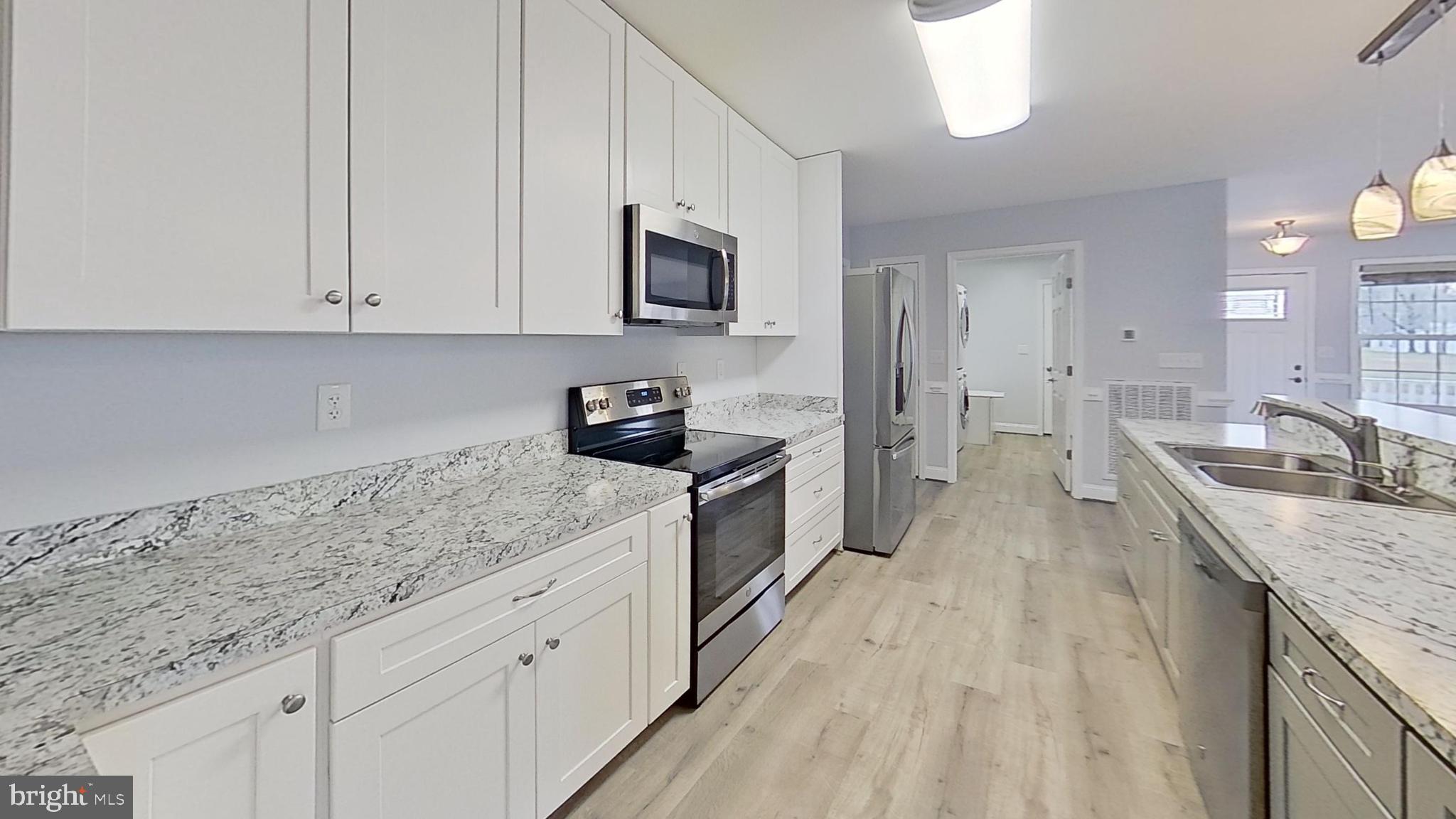 95 Rolando Drive Colonial Beach, VA 22443 - Photo 18 of 39 a kitchen with granite countertop a sink dishwasher stove and white cabinets with wooden floor