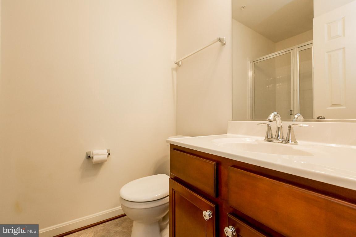 8042 Wright Place, Unit 103 Jessup, MD 20794 - Photo 19 of 22 a bathroom with a granite countertop sink a toilet and a mirror