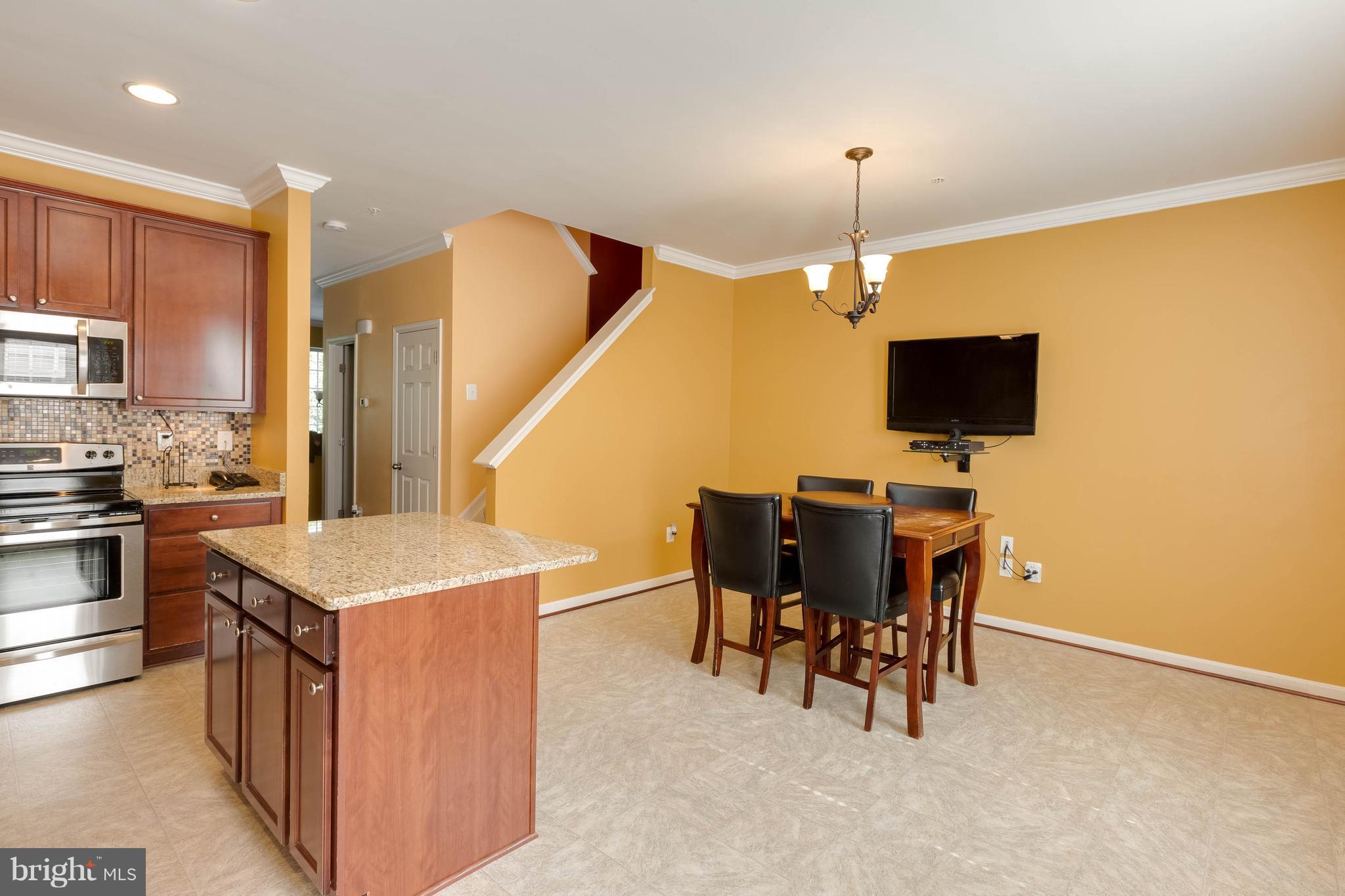 8042 Wright Place, Unit 103 Jessup, MD 20794 - Photo 7 of 22 a kitchen that has a microwave a stove a sink a dining table and chairs