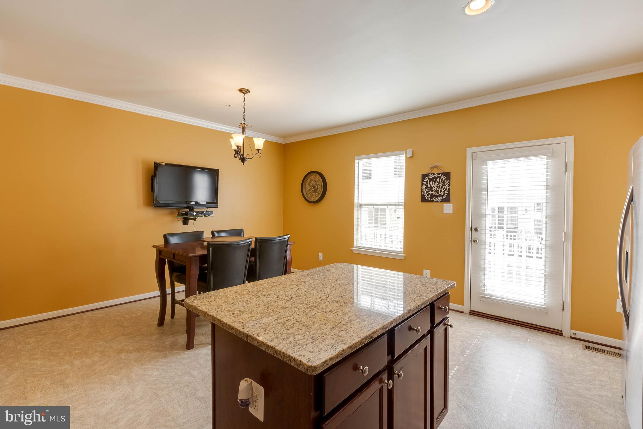 8042 Wright Place, Unit 103 Jessup, MD 20794 - Photo 9 of 22 a kitchen with a table chairs and flat screen tv