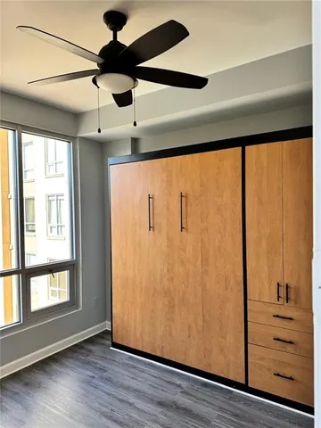 an empty room with wooden floor fan and windows