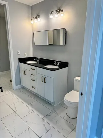 a bathroom with a granite countertop toilet a sink and mirror