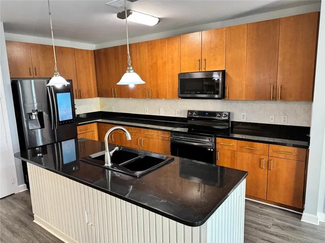 a kitchen with stainless steel appliances granite countertop a sink a stove and a refrigerator