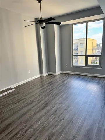 a view of an empty room with wooden floor and a window