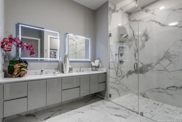 a bathroom with a double vanity sink mirror and shower