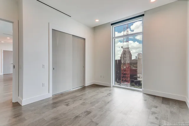 a view of an empty room with wooden floor and closet