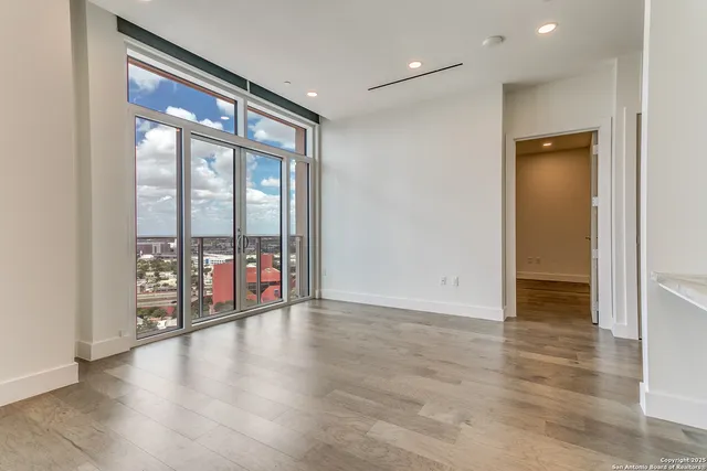 a view of empty room with wooden floor and fan