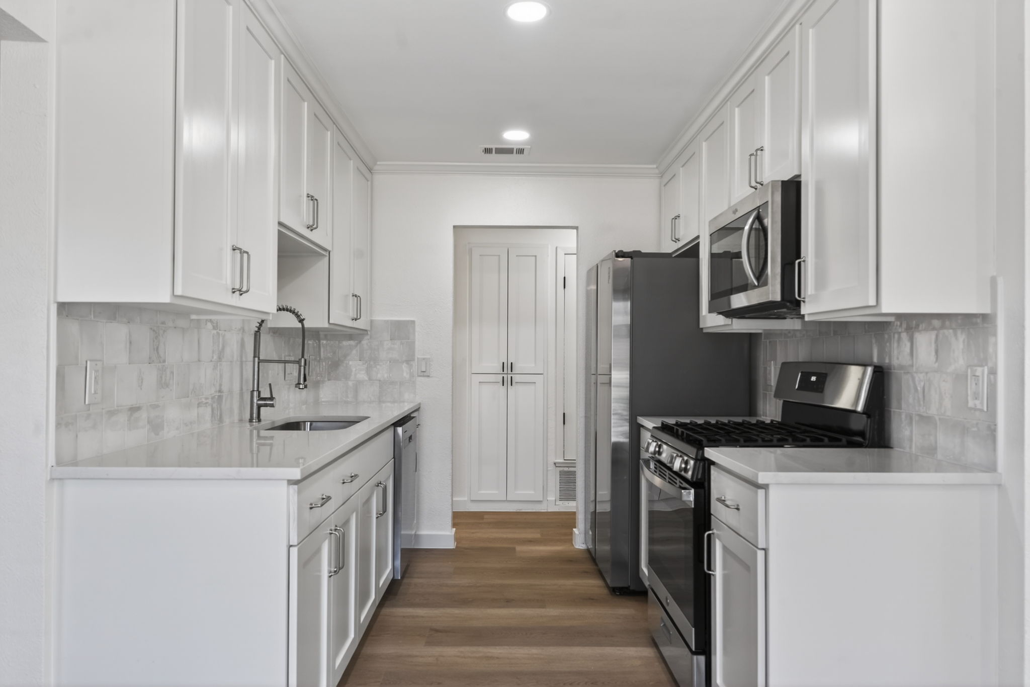8400 Seminary Ridge Drive Austin, TX 78745 - Photo 13 of 37 Kitchen with stainless steel appliances, white cabinets, light stone countertops, dark wood-style flooring, and crown molding
