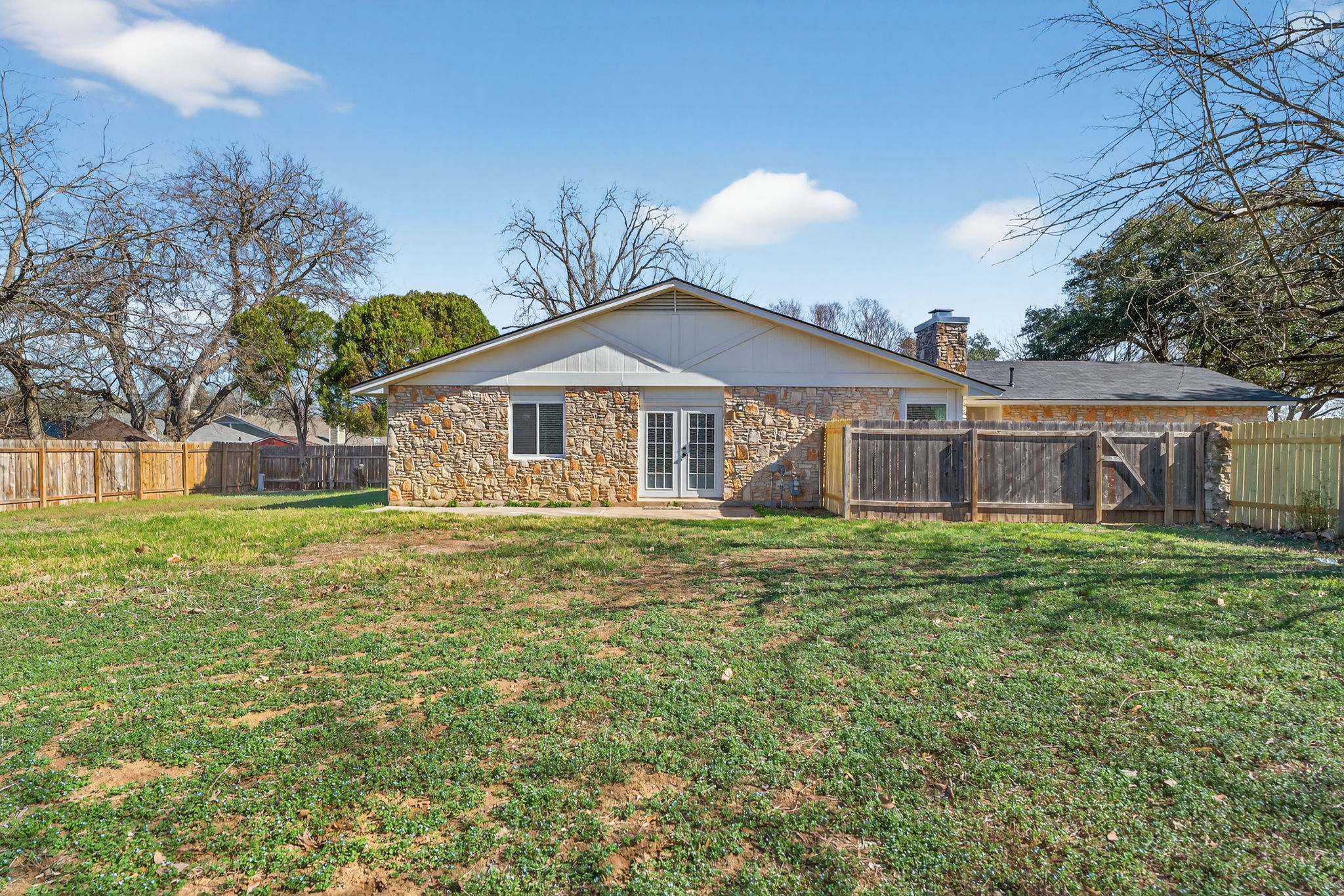 8400 Seminary Ridge Drive Austin, TX 78745 - Photo 29 of 37 Rear view of house with a chimney, a fenced backyard, stone siding, and french doors