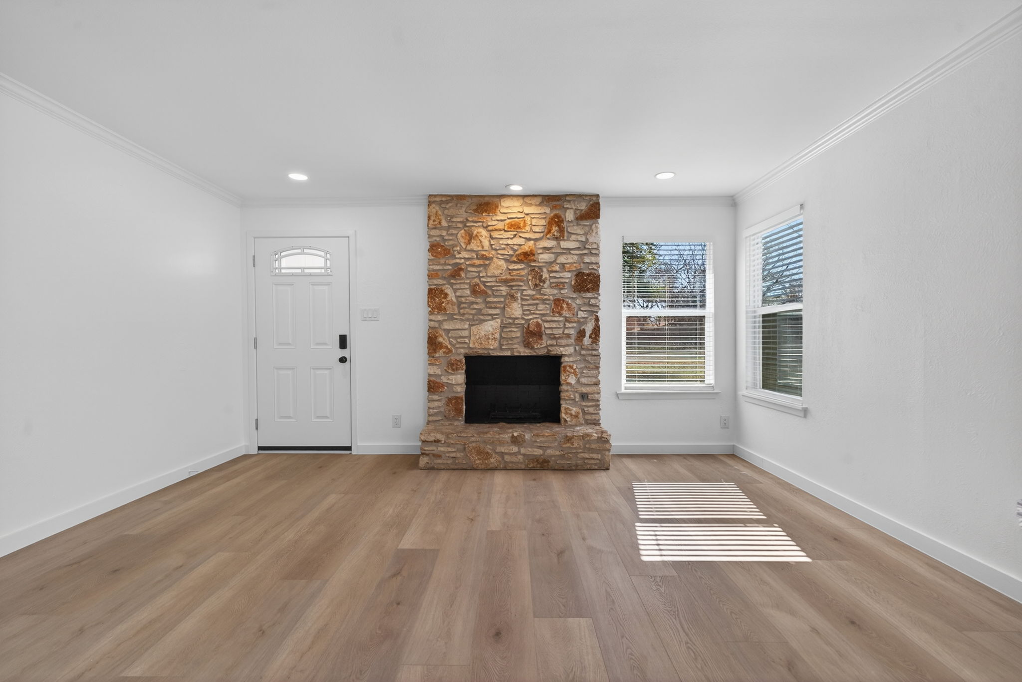 8400 Seminary Ridge Drive Austin, TX 78745 - Photo 7 of 37 Unfurnished living room with light wood finished floors, crown molding, and a fireplace