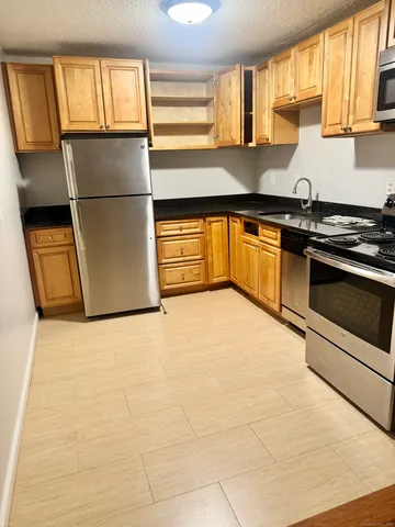 a kitchen with granite countertop a refrigerator and a stove top oven