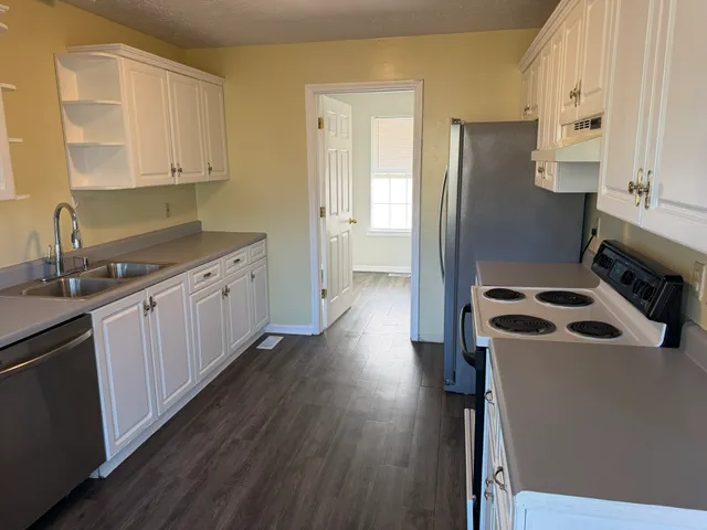 a kitchen with granite countertop a refrigerator a sink and wooden cabinets