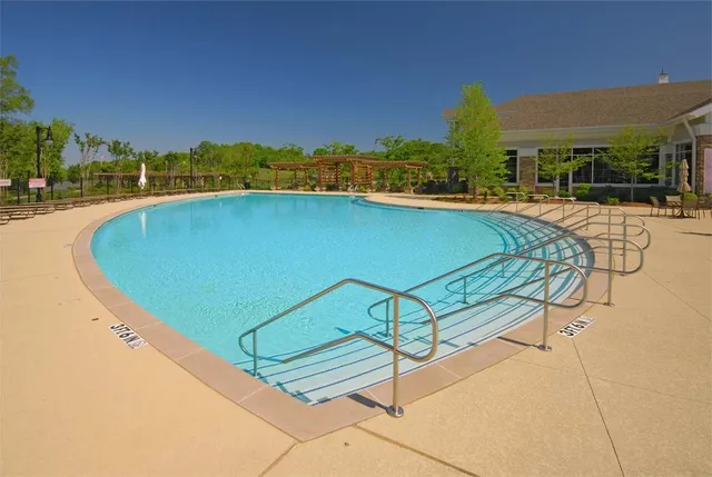 a view of a swimming pool with lawn chairs under an umbrella and palm trees
