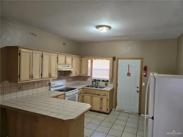 a kitchen with a sink a refrigerator and cabinets
