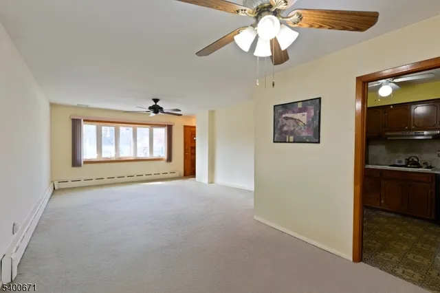 a view of an empty room with a window and a kitchen
