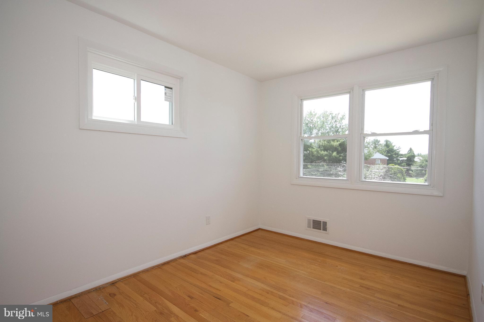 6936 Blanche Road Baltimore, MD 21215 - Photo 11 of 15 an empty room with wooden floor and windows