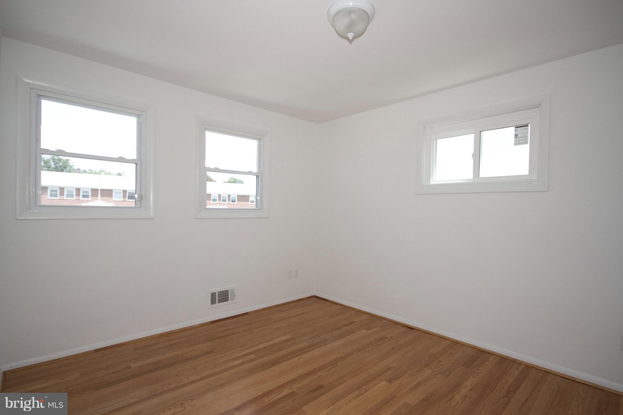 6936 Blanche Road Baltimore, MD 21215 - Photo 10 of 15 an empty room with wooden floor and windows