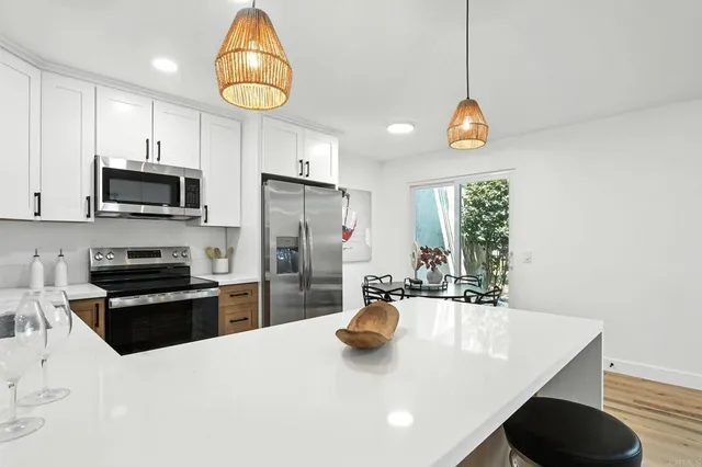 a kitchen with stainless steel appliances a sink a stove a refrigerator cabinets and a dining table