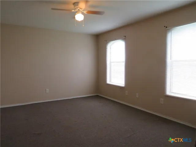 an empty room with a window and a fan