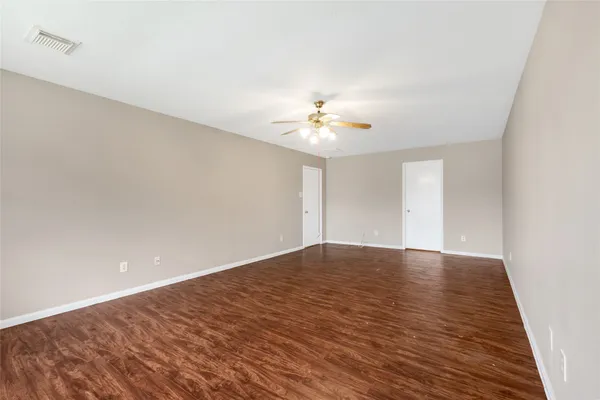 a view of an empty room and chandelier fan