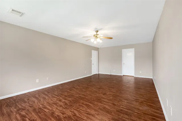 a view of an empty room and chandelier fan