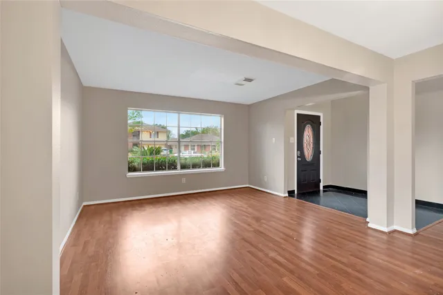a view of an empty room with glass door and wooden floor
