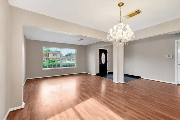 a view of a room with wooden floor and chandelier