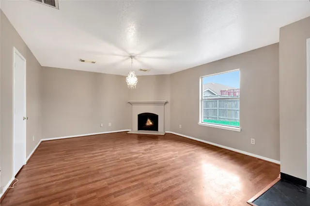 an empty room with windows fireplace and wooden floor