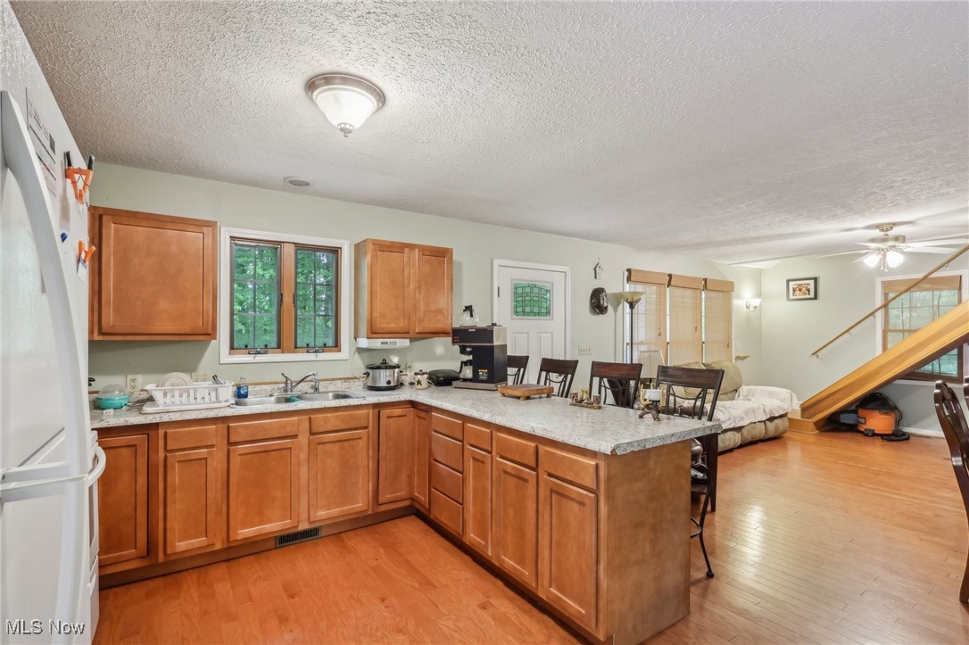 2490 Dodgeville Road Rome, OH 44085 - Photo 8 of 42 Kitchen featuring a sink, a kitchen breakfast bar, freestanding refrigerator, a textured ceiling, and a peninsula