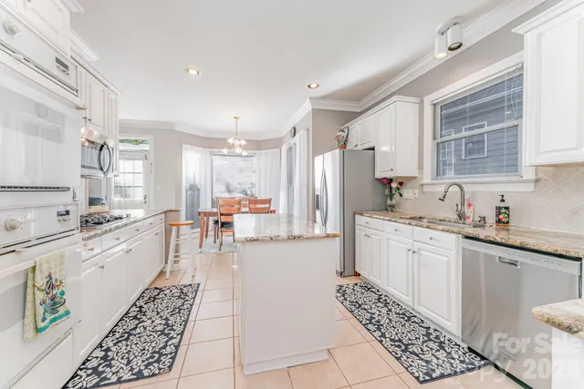 a large kitchen with stainless steel appliances kitchen island granite countertop a sink and cabinets